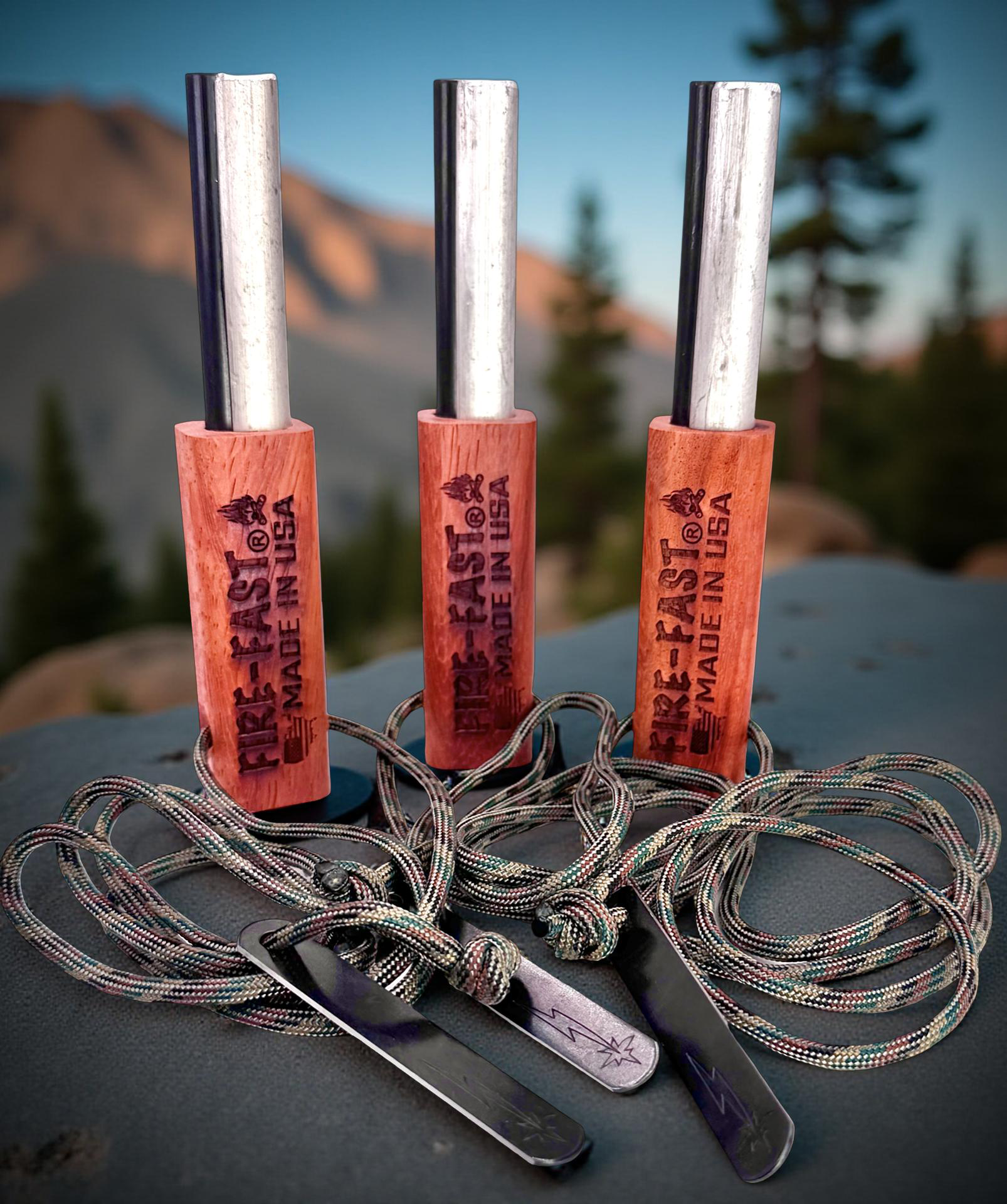 Fire-Fast Kamper Trio – three Kamper Lanyard ferro rods with 40" paracord lanyards and strikers against mountain backdrop – buy 3 and save promotion.