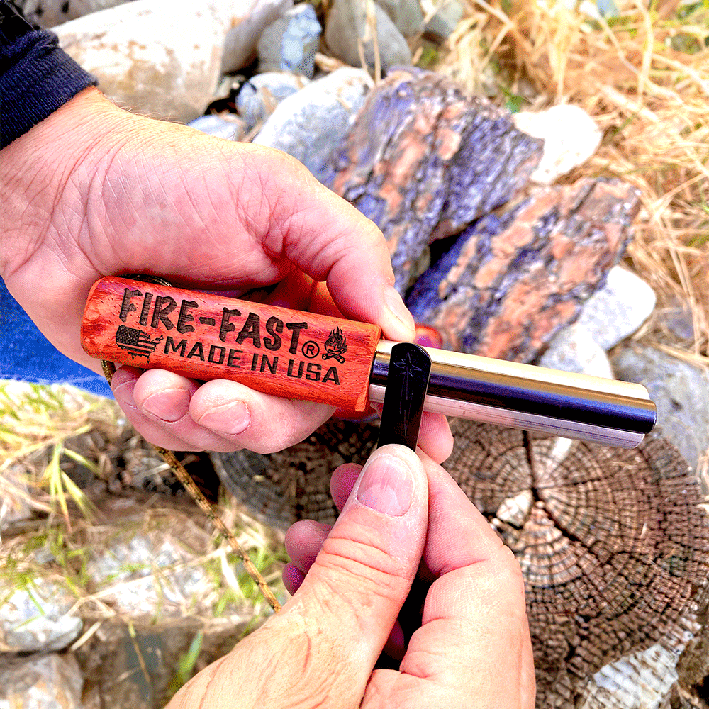 Close-up of hands using Fire-Fast Trekker fire starter, showing 'MADE IN USA' engraved hardwood handle and ferro rod with striker in outdoor setting
