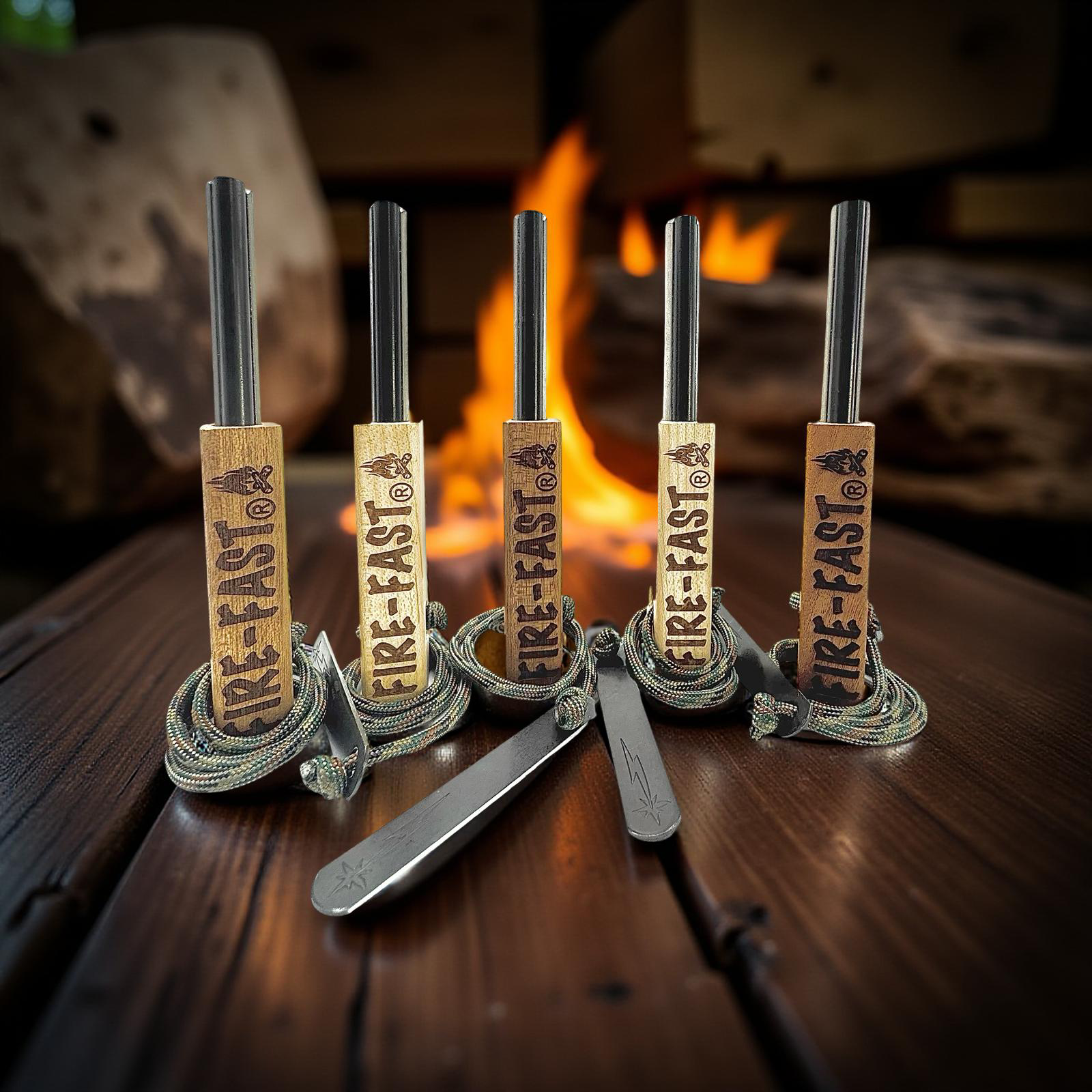 Five Fire-Fast ferro rod fire starters with wooden handles and strikers arranged in front of a roaring cabin fireplace – Buy 4 Get 1 Free promotion.